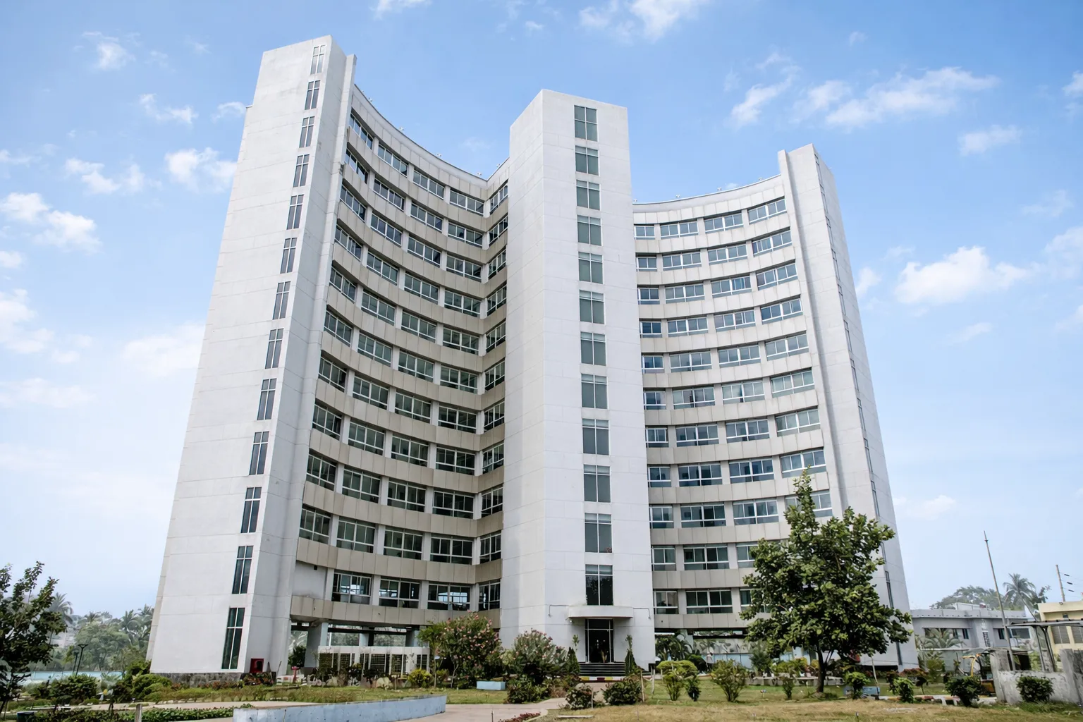 Curved main building of the hotel seen from the grounds under a blue sky