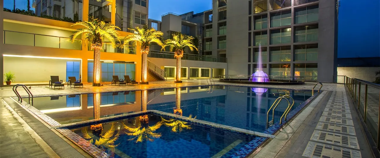 Swimming pool with palm-lined deck beside the hotel block