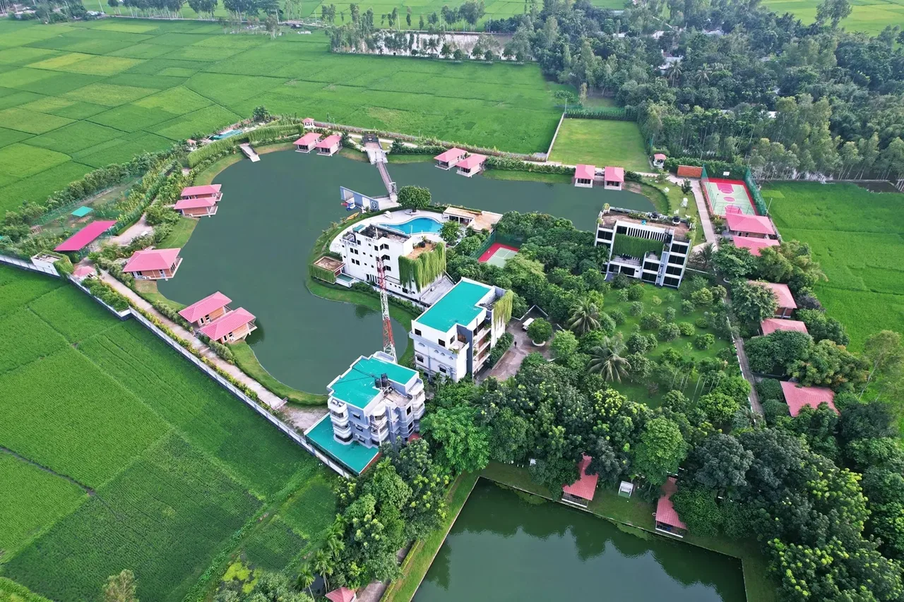 Aerial view of the resort buildings, villas and ponds among green fields