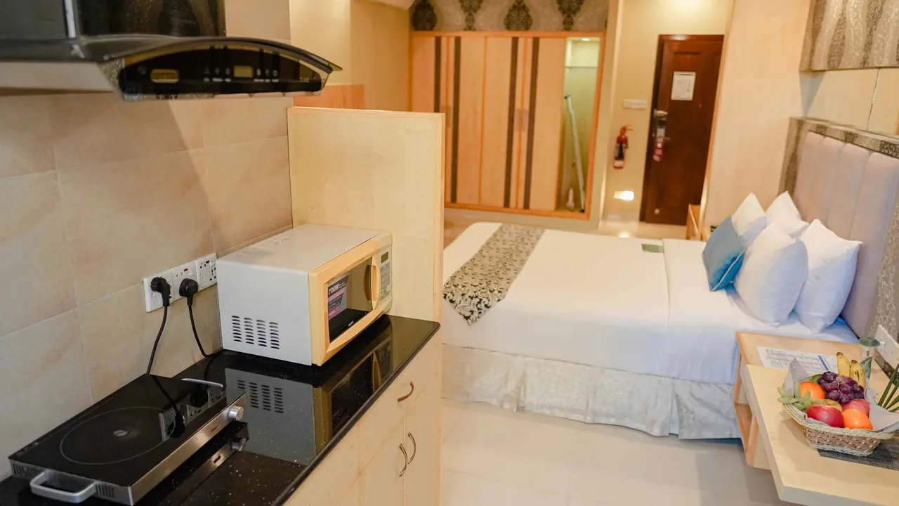 Room with a bed and a kitchenette with microwave and cooktop at Ascott The Residence Dhaka