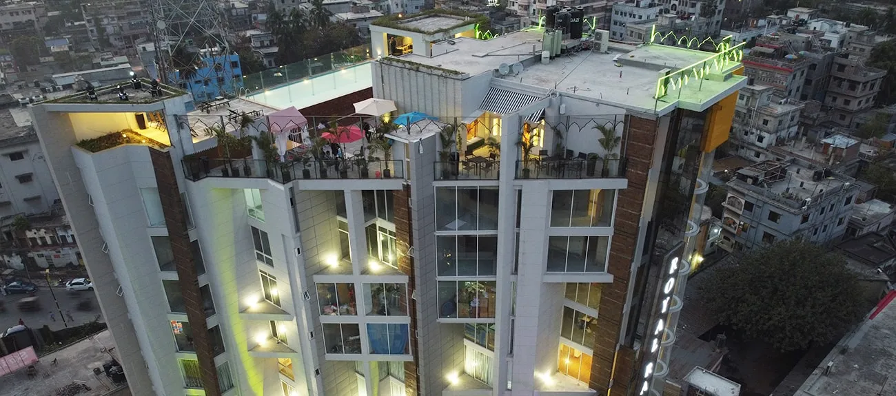 Hotel tower with a lit rooftop seen from above at night
