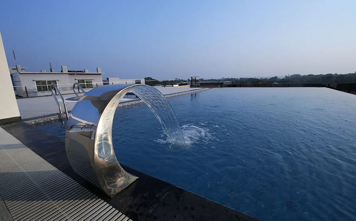 Infinity pool with a steel water feature at dusk