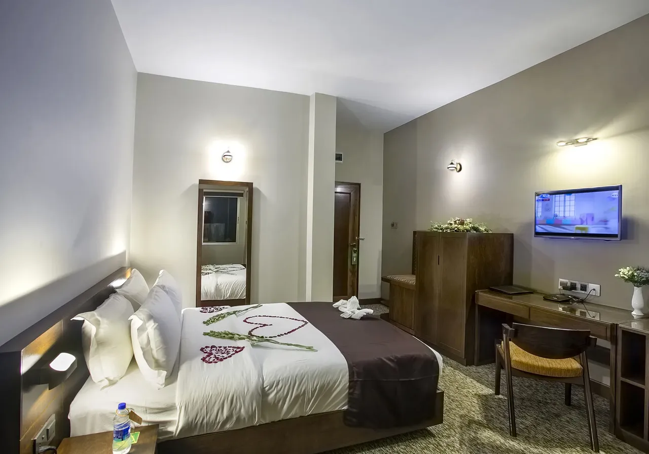 Guest room with a bed, desk and wall-mounted television