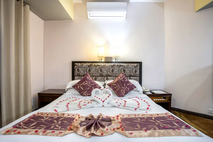 Deluxe room with a double bed and maroon runner
