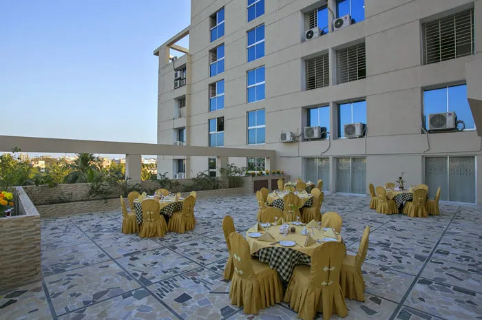 Rooftop dining terrace with round tables beside the hotel block