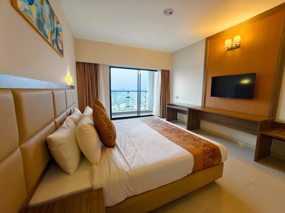 Room with a large bed, TV and a balcony window