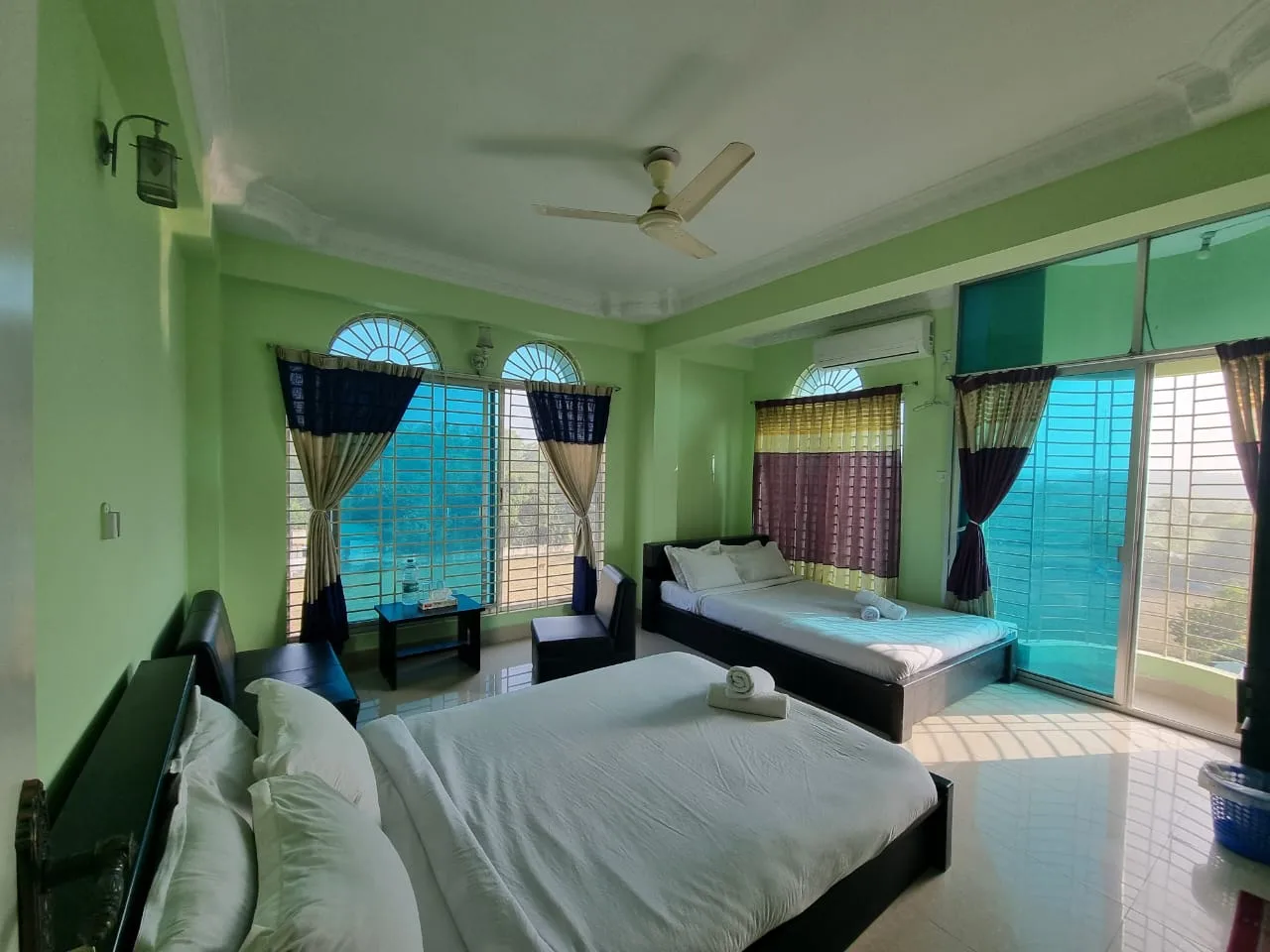 Guest room with a double bed and a second bed by large windows