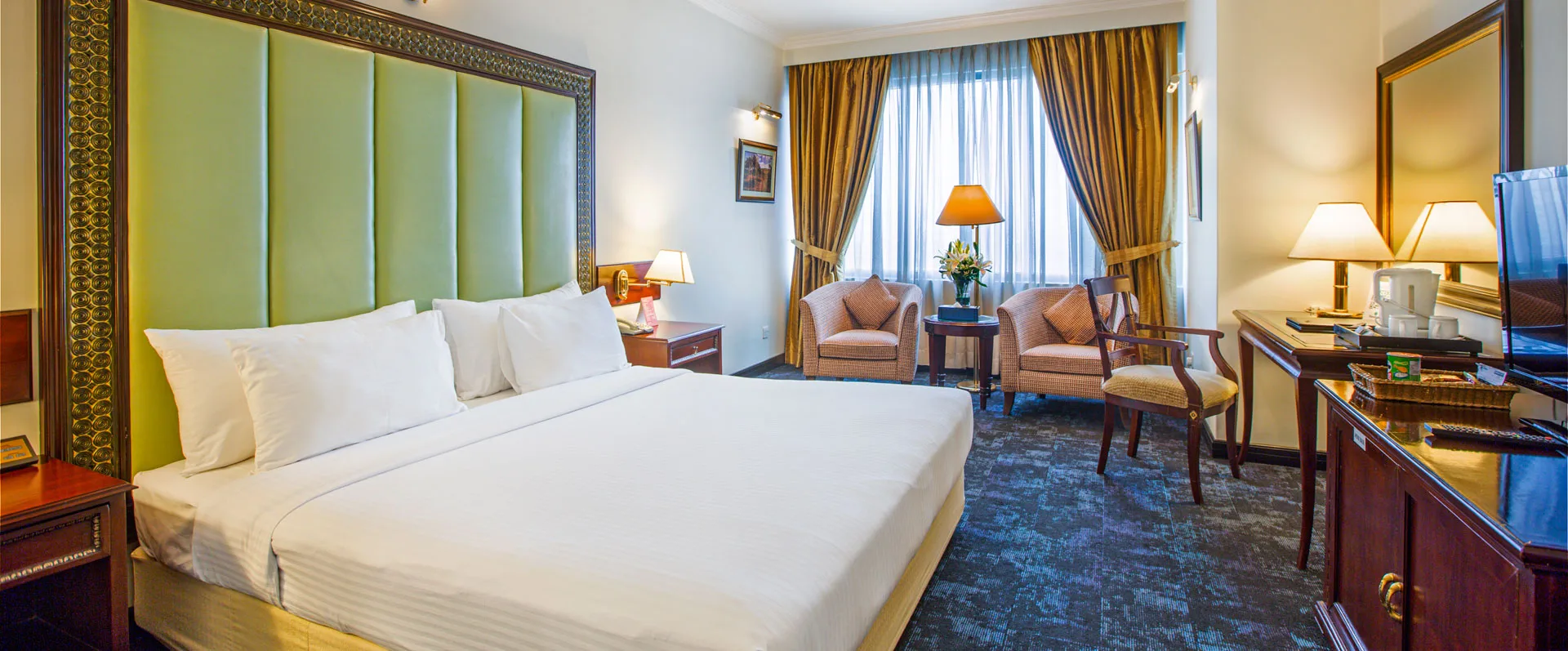 Guest room with a king bed and green headboard at Hotel Sarina