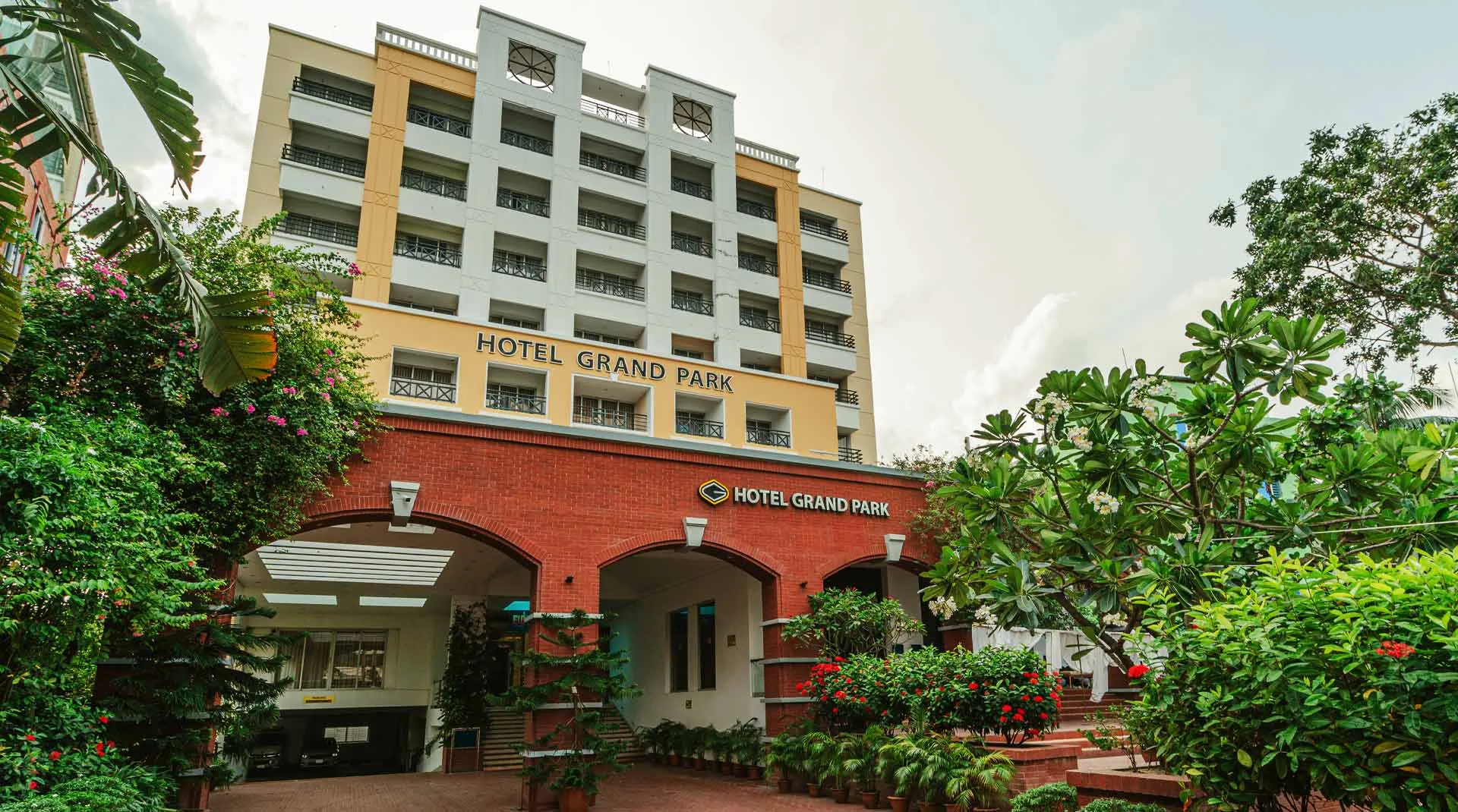 Hotel Grand Park tower with a red-brick arcade entrance by day