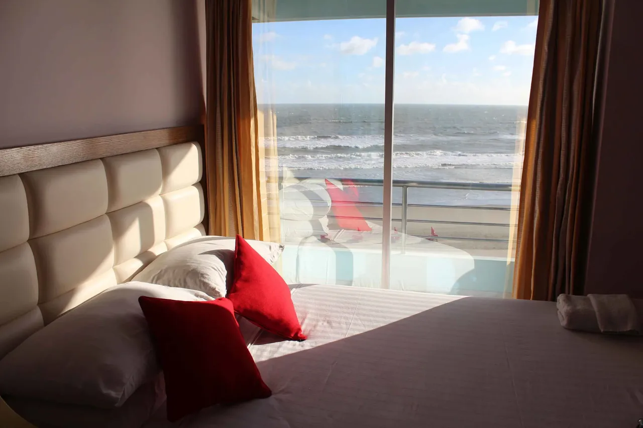 Room with a bed beside a balcony door facing the sea