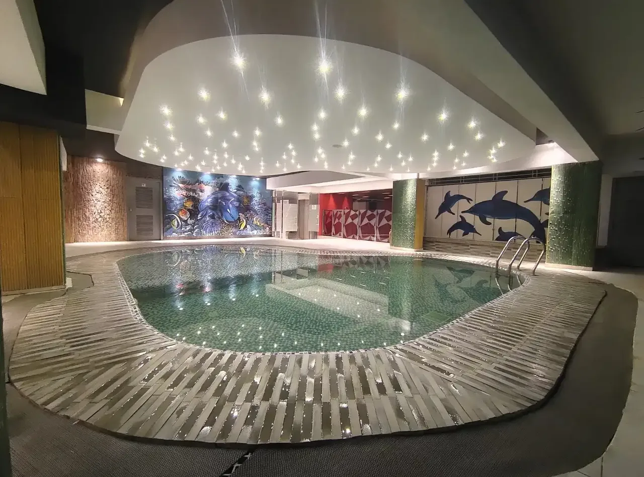 Indoor swimming pool with dolphin murals at Royal Pearl Suites