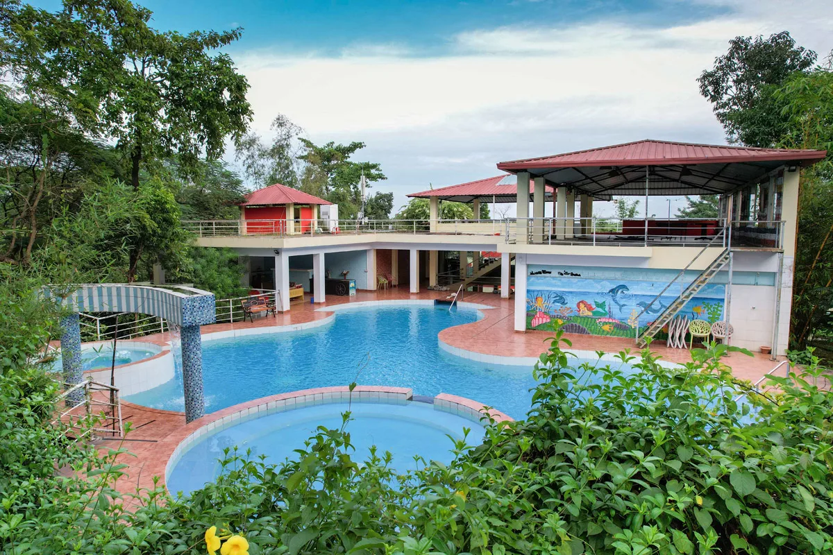 Swimming pool and pavilions with wooded hills behind